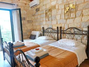 two beds in a bedroom with a stone wall at Villa Constancia in Stalos +38 photos
