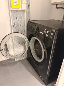 a black washing machine sitting in a room at Chez Mathieu in Saint-Dizier