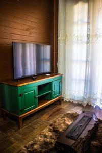 a flat screen tv on a green cabinet in a room at Império Cabanas in Urubici