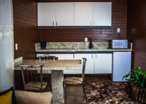 a kitchen with white cabinets and a marble counter top at Império Cabanas in Urubici