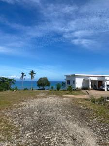 a white building with palm trees in front of the ocean at GJ House in Esperanza, Poro, Camotes in Mactan