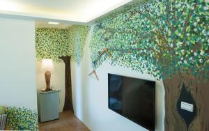 a room with a mural of a tree and a tv at Go Go Fun in Luodong