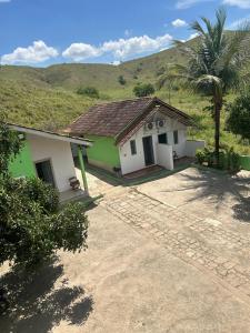 a green and white house with a palm tree at Pousada do pc in Bom Jesus do Itabapoana