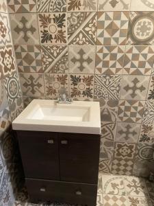 a bathroom with a sink and a tiled wall at Yellow House, Private Apartment, Centro Arteaga in Arteaga
