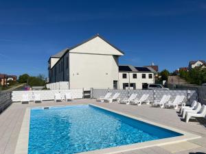a swimming pool with lounge chairs and a house at Comfortable holiday homes with a summer pool in Jarosławiec