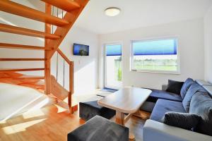 a living room with a blue couch and a table at Comfortable holiday homes with a summer pool in Jarosławiec