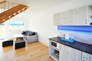 a kitchen and living room with a couch and a table at Comfortable holiday homes with a summer pool in Jarosławiec