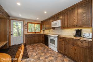 a kitchen with wooden cabinets and white appliances at Breezy Woods - Tobermory Waterfront in Tobermory