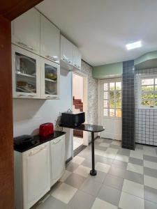 a kitchen with white cabinets and a table in it at BeInn - Short Stay Collection Penedo in Itatiaia