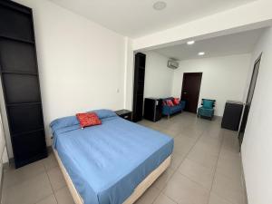 a bedroom with a blue bed and a room with a chair at Habitación en el Tornero in SamborondÃ³n