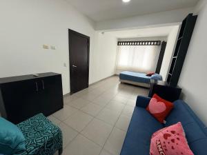 a living room with a blue couch and a bed at Habitación en el Tornero in SamborondÃ³n