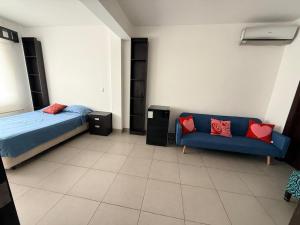 a bedroom with a blue bed and a couch at Habitación en el Tornero in SamborondÃ³n