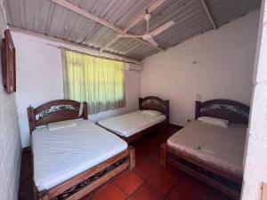 two beds sitting in a room with a window at Ricaurte casa campestre in Ricaurte +10 photos