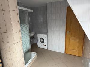 a small bathroom with a washing machine and a door at HannaBella Vendégház & Wellness in Miskolc