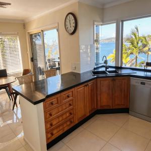 a kitchen with a sink and a clock on the wall at Stunning Absolute Waterfront With Private Jetty in Fishing Point