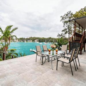 a patio with a table and chairs and a body of water at Stunning Absolute Waterfront With Private Jetty in Fishing Point
