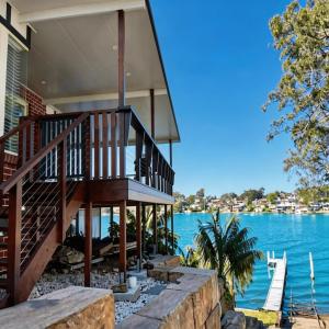a house with a staircase on the water at Stunning Absolute Waterfront With Private Jetty in Fishing Point