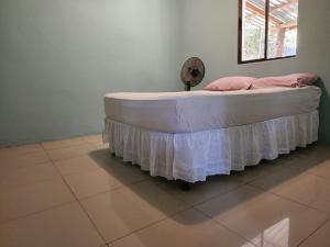 a bed with a white bed skirt on it at Calala House in Balgue