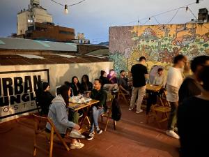 a group of people sitting at tables in front of a wall at Urban Jungle Hostel in San Miguel de Tucumán