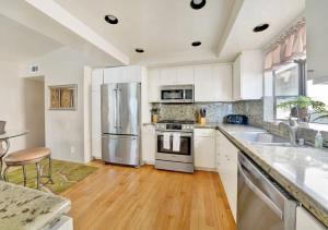 a kitchen with white cabinets and a stainless steel refrigerator at Contemporary Value 4 Bdr, with Rooftop Deck- 303 home in Newport Beach