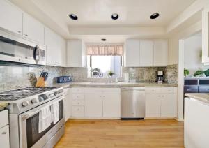 a kitchen with white cabinets and a stove top oven at Contemporary Value 4 Bdr, with Rooftop Deck- 303 home in Newport Beach