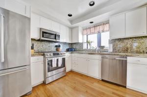 a kitchen with white cabinets and stainless steel appliances at Contemporary Value 4 Bdr, with Rooftop Deck- 303 home in Newport Beach