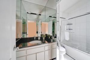 a bathroom with a sink and a toilet and a mirror at Contemporary Value 4 Bdr, with Rooftop Deck- 303 home in Newport Beach
