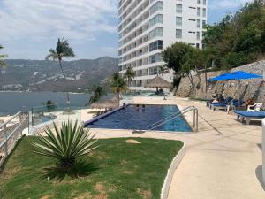 a swimming pool in front of a tall building at Paraiso Azul in Acapulco
