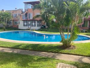 a swimming pool in front of a house with a palm tree at Casa Tortuga in Ixtapa