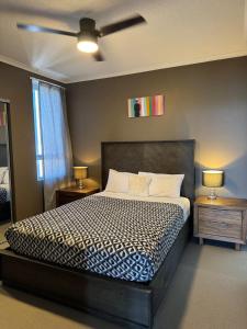 a bedroom with a bed with a ceiling fan at The Perfect Host @ Curtis Apartments in Gladstone