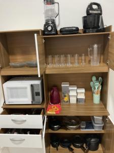 a microwave oven sitting on top of a kitchen shelf at CONDOMINIO JT ll in Ubatuba