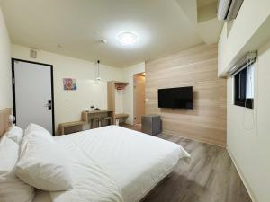a bedroom with a white bed and a flat screen tv at 海洋星空民宿 in Magong