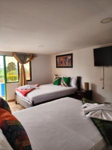 a hotel room with two beds and a tv at Alojamiento el jardin in Filandia +49 photos