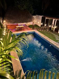 a swimming pool at night with a table and chairs at Hotel Framfor Inn Chetumal in Chetumal