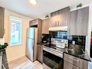 a kitchen with wooden cabinets and a stainless steel refrigerator at Cozy 1BR Apt perfect for Couple in Longueuil