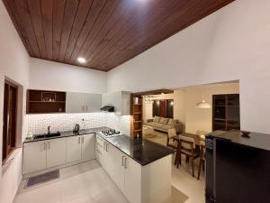 a kitchen with white cabinets and a living room at Citron Cottage in Kandy +8 photos