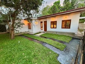 a white house with a tree in the yard at Citron Cottage in Kandy