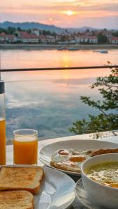 a table with two plates of food and a glass of orange juice at โรงแรมดีวิว โกลเด้นไทรแองเกิ้ล เชียงแสน - Dview Golden Triangle Hotel Chiangsaen in Golden Triangle