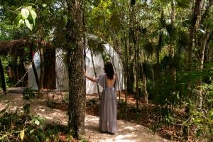 a woman standing next to a tree in a forest at Jungle Glamping K'u' Kuk in Chemuyil