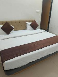 a large bed with brown and white sheets and pillows at Hotel Viny villa in Udaipur +1 photo