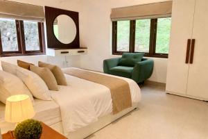 a bedroom with a bed and a chair and a mirror at Citron Cottage in Kandy