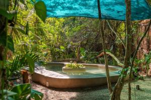 a hot tub in the middle of a forest at Jungle Glamping K'u' Kuk in Chemuyil