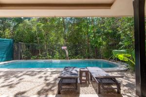 a swimming pool with two benches and a picnic table at Jungle Glamping K'u' Kuk in Chemuyil