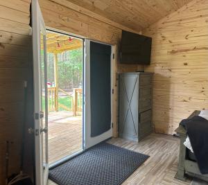 an open door in a wooden room with a television at Off the Road Oasis in Lufkin