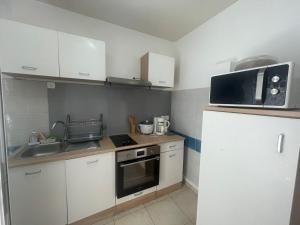 a small kitchen with a sink and a microwave at SOLEY City Break 13 in Les Abymes