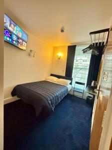 a hotel room with a bed and a television at Jubilee Hotel Kensington in London