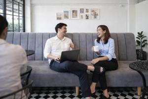 a man and woman sitting on a couch with a laptop at Siri Space สิริ สเปซ in Ban Khlong Nung (1)
