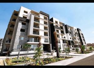 a large apartment building with palm trees in front of it at Modern Flat at Shiekh Zayed in Sheikh Zayed