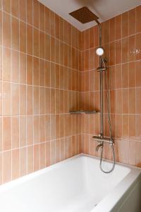a bath tub with a shower in a tiled bathroom at Hotelarrive Seoulful in Seoul