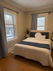 a bedroom with a large bed and two windows at A home in Niagara falls- The Maple and Mist in Niagara Falls